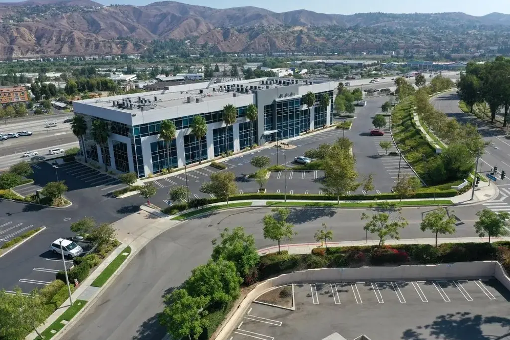 Aerial view of a landscaped office park with parking, street trees, and mountains behind