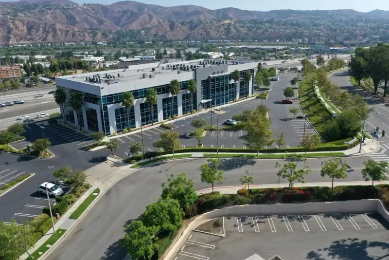 Aerial view of a landscaped office park with parking, street trees, and mountains behind